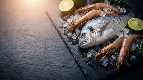 Shrimp and a whole fish on ice with lime.